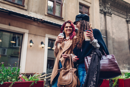 Outdoor shot of young women walking on city street. and having coffee. Happy friends talking and having funの写真素材