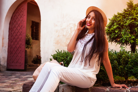 Beautiful tourist girl talking on phone outdoors. Middle eastern woman calling friends having restの写真素材