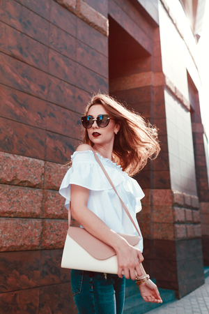 Outdoor portrait of a young beautiful happy woman on city street. Model wearing stylish summer clothing and accessories and spinsの写真素材