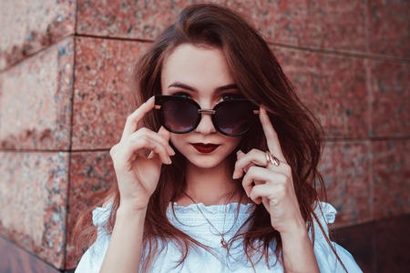 Outdoor portrait of beautiful stylish woman in glasses on street. Fashion model wearing summer clothing and accessoriesの写真素材