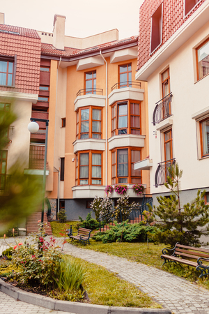 New multi-storey residential building. Modern house dyed in red and orange colors with garden besideの写真素材
