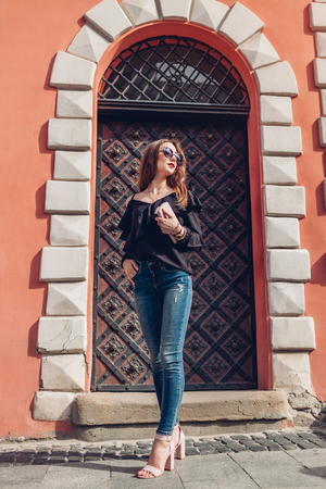 Outdoor portrait of a beautiful stylish woman in sunglasses on city street. Fashion model wearing summer clothing and accessories. Lady holding a handbagの写真素材