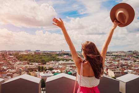 Young female tourist with raised hands looking on Lviv, Ukraine from viewpointの写真素材