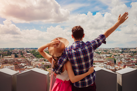Young couple of tourists with raised hands looking on Lviv, Ukraine from viewpointの写真素材