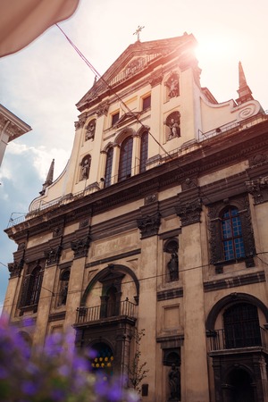 Catholic church of St. Peter and Paul in Lviv, Ukraine. Ancient cathedral on sky background with flowers in frontの写真素材