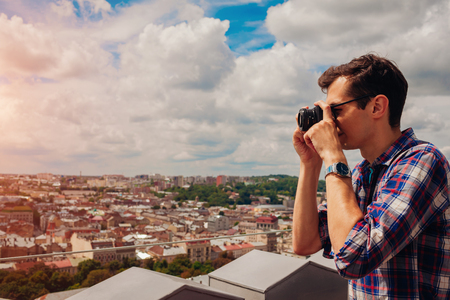 Portrait of happy young man, tourist with camera taking pictures of old city Lviv from viewpoint.の写真素材