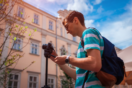 Portrait of happy young man, tourists with camera taking pictures of old city.の写真素材
