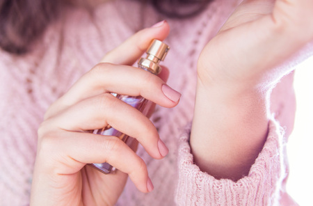 Young woman applying perfume on her wrist. Girl holding bottle and sprays perfume. Cosmeticsの写真素材