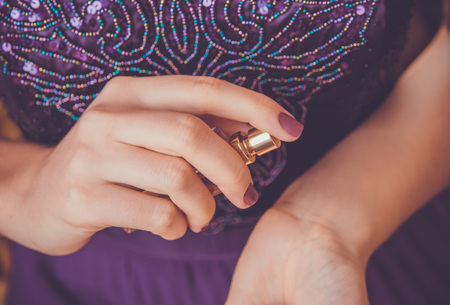 Young woman applying perfume on her wrist. Girl holding bottle and sprays perfume. Cosmeticsの写真素材