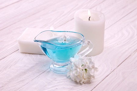 Spa setting: body lotion, soap, candles, oil, towel with lilac on wooden background. Body careの写真素材