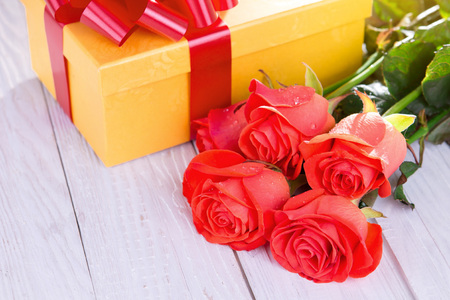 Present for Valentines day with roses on wooden background. Gift box with flowersの写真素材