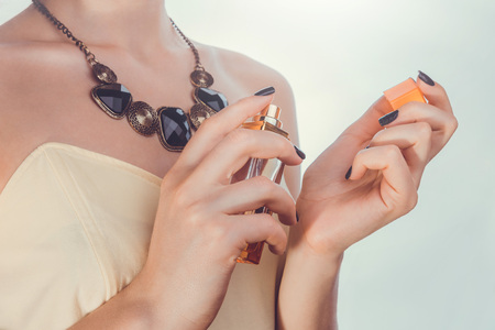 Young woman applying perfume on her wrist. Girl holding bottle and sprays perfume. Cosmeticsの写真素材