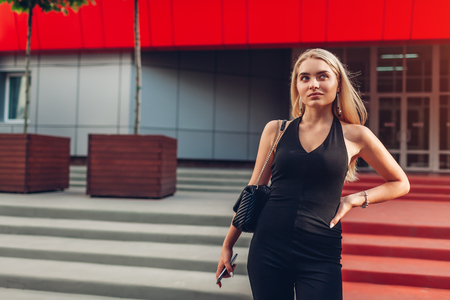 Young blonde businesswoman waiting for colleagues by modern business center in city. Confident, powerful and successful women conceptの写真素材