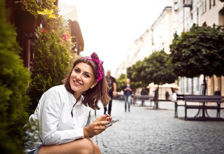 Young beautiful woman uses wifi on her phone in old city centerの写真素材