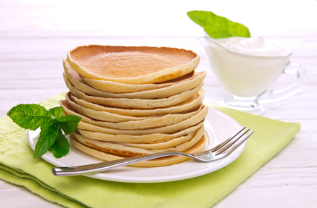 Stack of pancakes with mint and sour cream on white wooden backgroundの写真素材