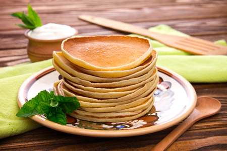 Stack of pancakes with mint and sour cream on rustic wooden backgroundの写真素材