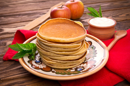 Stack of pancakes with mint, apples and sour cream on rustic wooden backgroundの写真素材