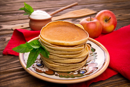 Stack of pancakes with mint, apples and sour cream on rustic wooden backgroundの写真素材