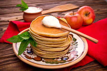 Stack of pancakes with mint, apples and sour cream on rustic wooden backgroundの写真素材