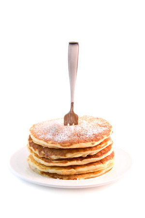 Stack of pancakes with sugar powder isolated on white background. Tasty dessert with fork stuck in itの写真素材