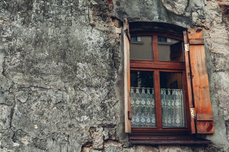 Single window in old wall. Ancient stone house. Wooden window with curtainsの写真素材