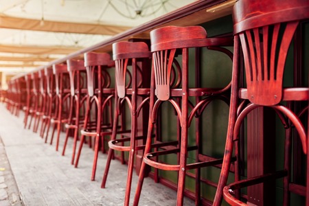 Empty cafe. Wooden chairs beside bar counter. Red vintage seats in rowの写真素材