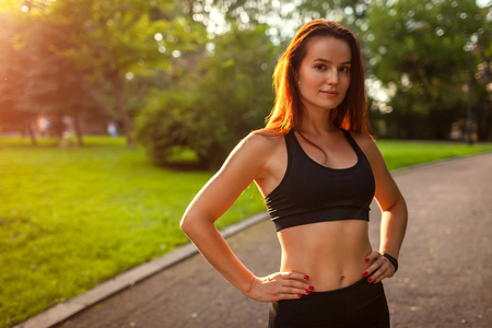 Young sportive woman looking at camera after workout in summer park. Sportswear. Strong woman having restの写真素材
