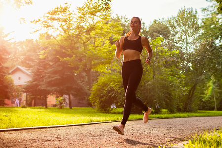 Young sportive woman running in summer park. Sportswoman jogging. Workout. Trainingの写真素材