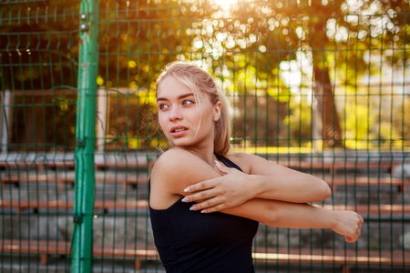 Young woman athlete warming up before running on sportsground in summer. Active lifestyleの写真素材