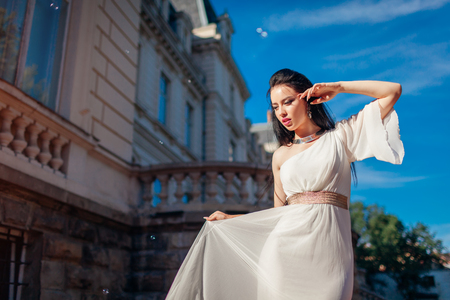 Beautiful woman wearing white wedding dress outdoors. One shoulder dress with accessories and jewelleryの写真素材