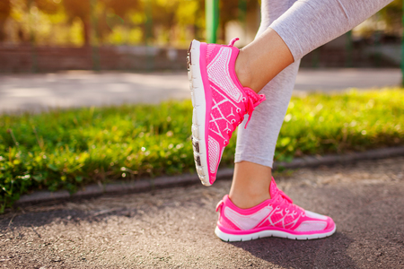 Young woman athlete warming up before running on sportsground in summer. Active lifestyleの写真素材