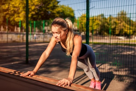 Young woman athlete doing push-ups on sportsground in summer. Healthy lifestyleの写真素材