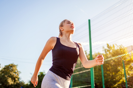 Young woman athlete running on sportsground in summer. Healthy way of lifeの写真素材