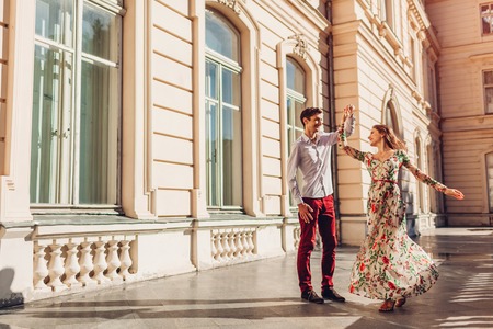 Young happy couple in love dancing by palace outdoors. Man and woman having fun in summer cityの写真素材