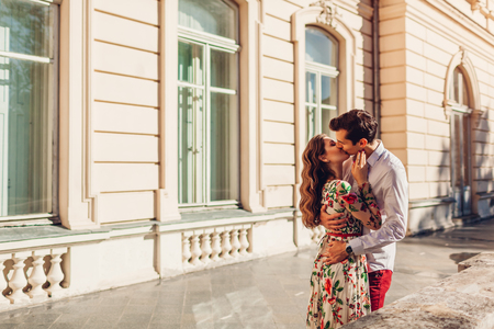 Young happy couple in love hugging and kissing outdoors. Romance. Man and woman walking by Pototskykh palace in Lvivの写真素材