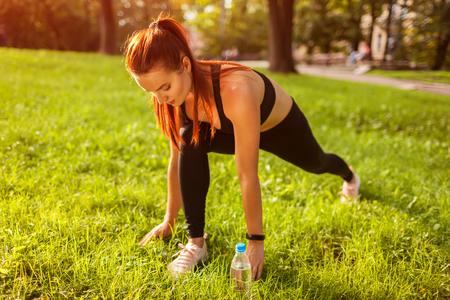 Young sportive woman doing lunges in summer park. Sportswoman stretching her lower body. Toning upの写真素材
