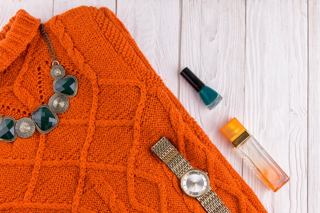 Orange sweater with jewellery, accessories and cosmetics. Female outfit on wooden backgroundの写真素材