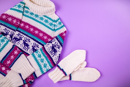 Winter female outfit. Set of clothes and accessories on purple background. Sweater with mittensの写真素材