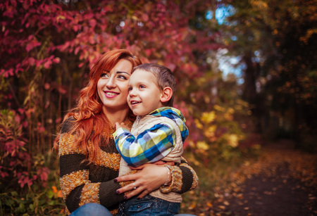 Happy mother and her little son walking and having fun in autumn forest. Kid is laughing.の写真素材