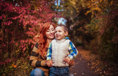 Happy mother and her little son walking and having fun in autumn forest. Kid is laughing. Family valuesの写真素材