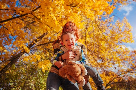 Happy mother and her little son walking and having fun in autumn forest.の写真素材