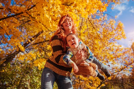 Happy mother and her little son walking and having fun in autumn forest.の写真素材