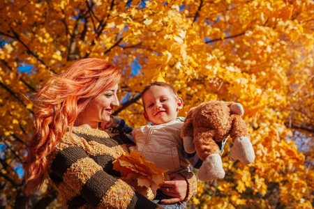 Happy mother and her little son walking and having fun in autumn forest. Woman holding her childの写真素材