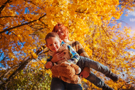 Happy mother and her little son walking and having fun in autumn forest.の写真素材