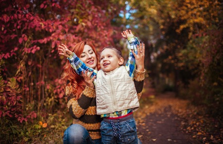 Happy mother and her little son walking and having fun in autumn forest. Kid is laughing. Family valuesの写真素材