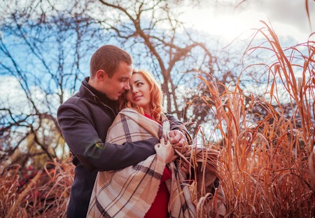 Young couple in love hugs in autumn forest among high grass. Happy people smilingの写真素材