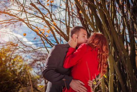 Young couple in love kisses in autumn forest under treesの写真素材