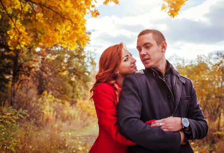 Young couple in love hugs in autumn forest among colorful trees. Romantic dateの写真素材