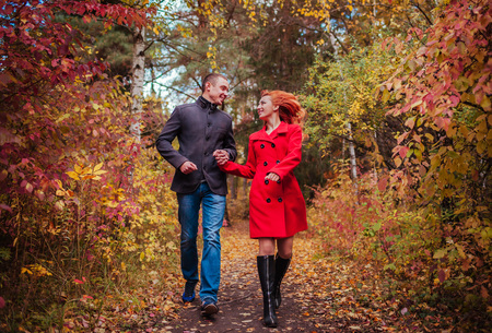 Young couple in love runs in autumn forest among colorful trees. People having funの写真素材