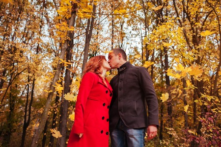 Young couple in love kisses in autumn forest among colorful treesの写真素材